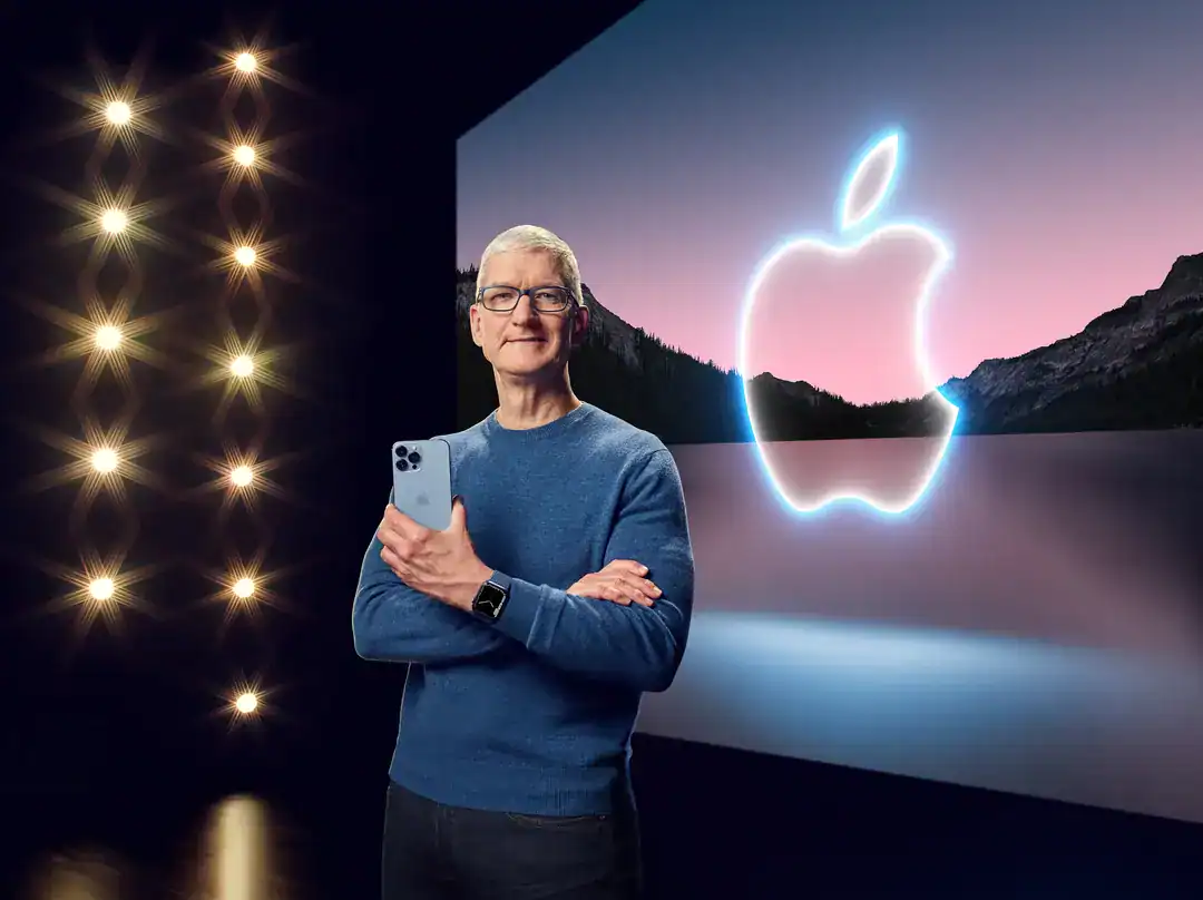 Apple logo glow behind Tim Cook presenting with iPhone, modern stage lights, serene landscape backdrop.