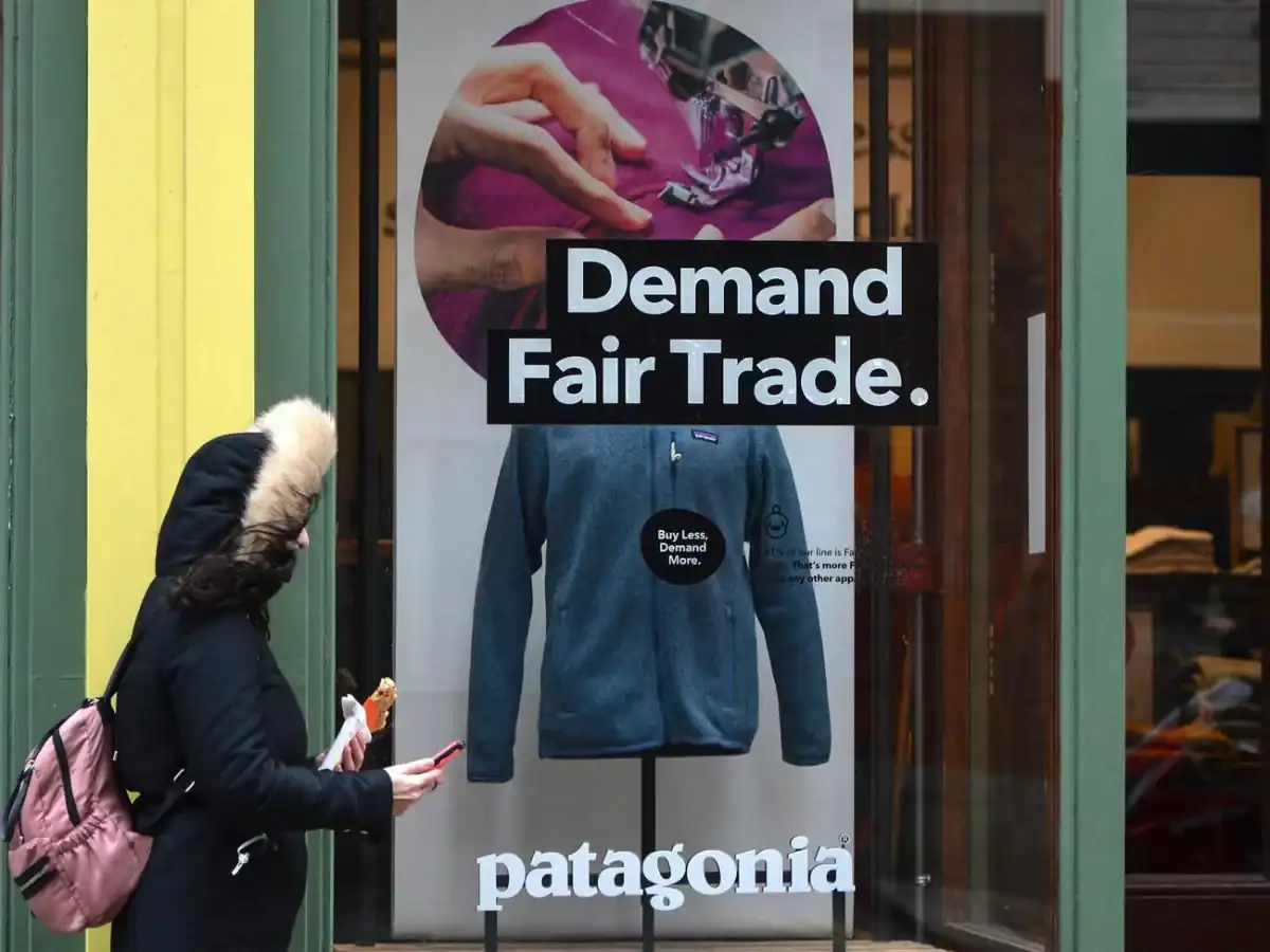 Patagonia storefront poster with blue jacket on display; Demand Fair Trade and patagonia wordmark.