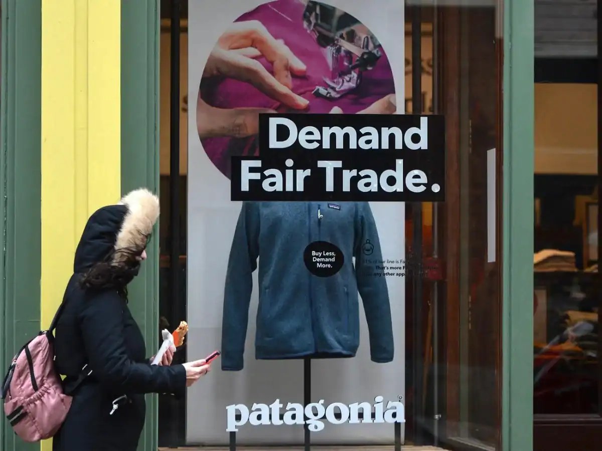 Patagonia storefront poster with blue jacket on display; Demand Fair Trade and patagonia wordmark.