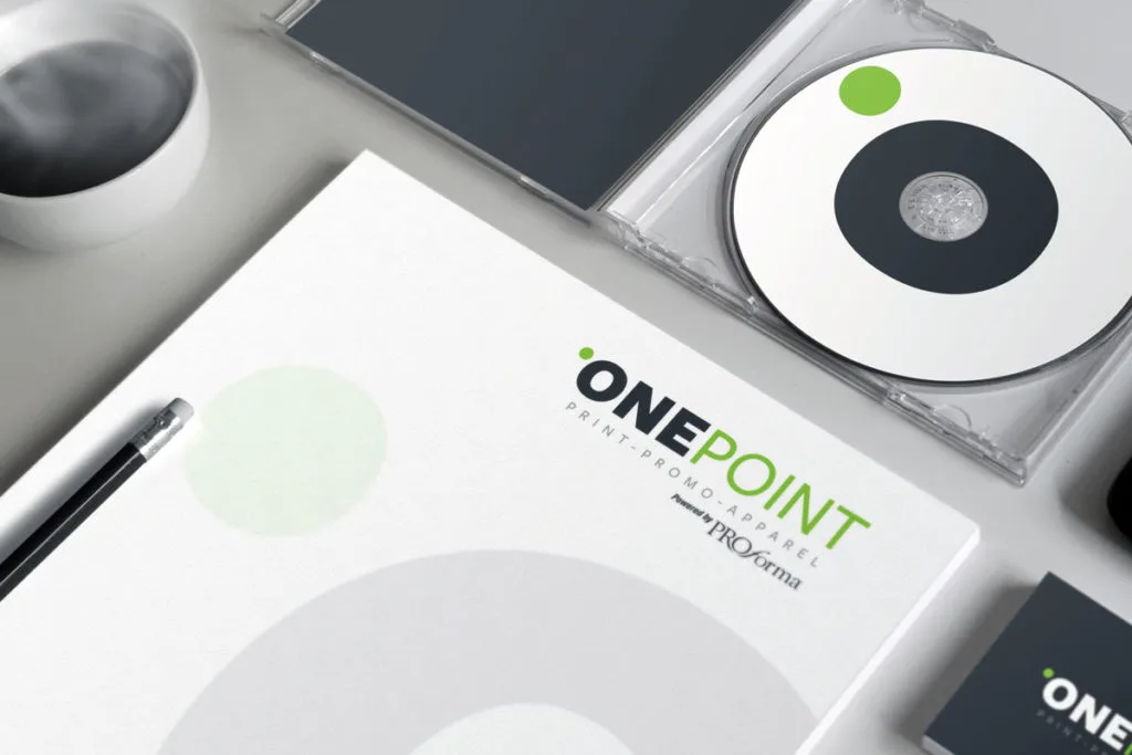 Onepoint Branding On A White Booklet Reading Print Promo Apparel, With A Cd And Pencil On A Light Desk.