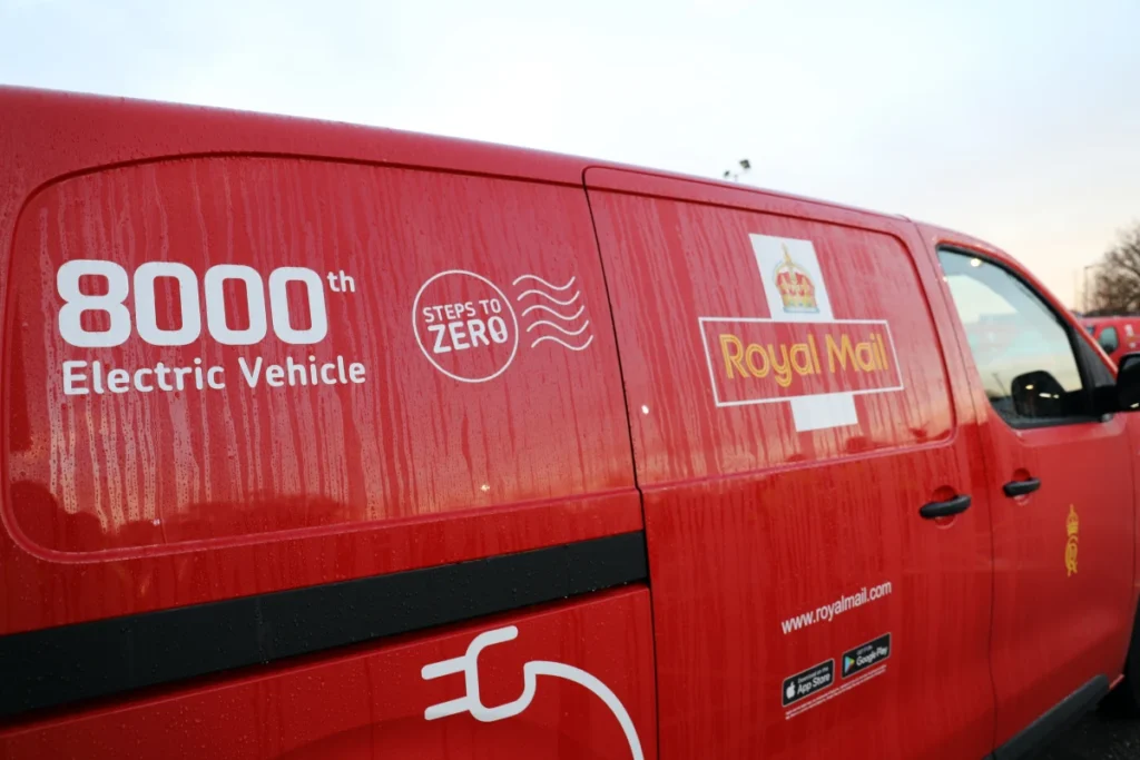 Royal Mail Van With 8000Th Electric Vehicle Branding, Says Steps To Zero; Red Delivery Van With Logo And Url.