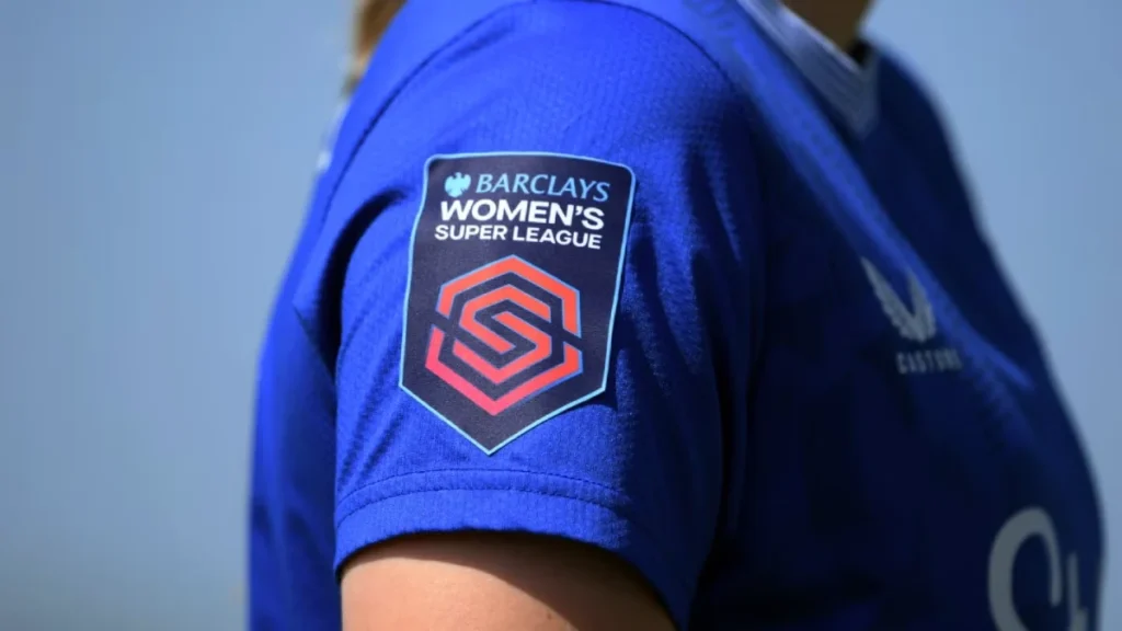 Barclays Women's Super League Patch On Blue Jersey Sleeve Featuring A Red Geometric Shield Logo.