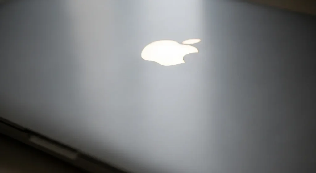 Apple Logo On A Silver Macbook Lid, Glowing, In Soft Focus.